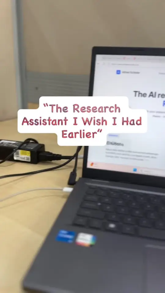 A laptop open on a desk with an on-screen caption reading "The Research Assistant I Wish I Had Earlier"